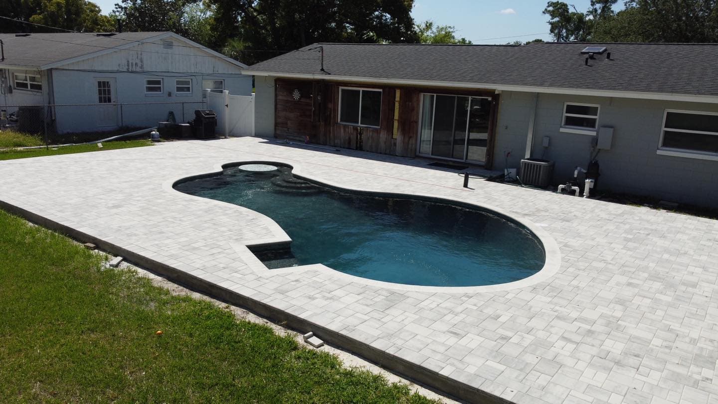 Aerial view of freeform pool with pavers